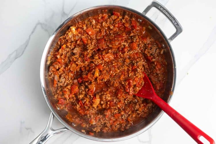 marinara added to cooked ground beef in a skillet.