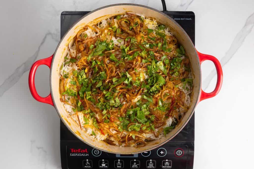 layered chicken biryani in a dutch oven.