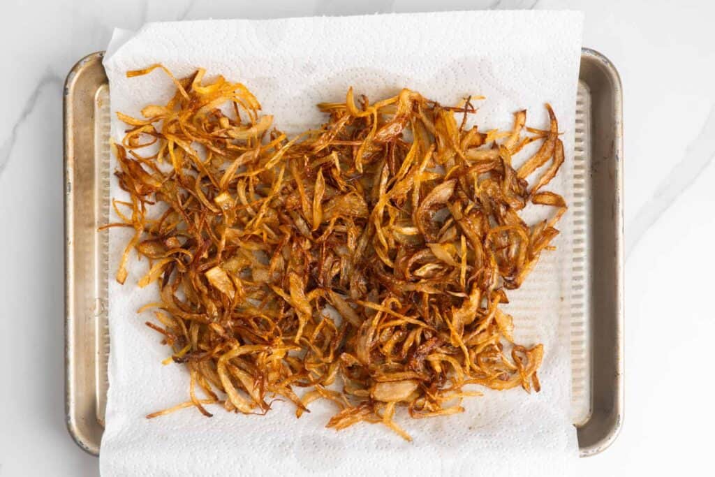 fried onions cooling on a paper towel.