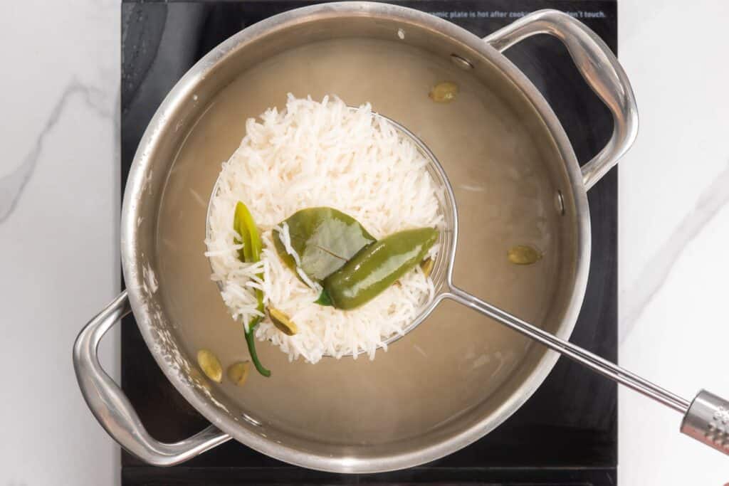 rice cooking with a chili and cardamom pods