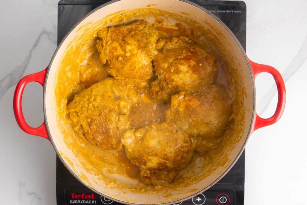 marinated biryani chicken cooking in a dutch oven
