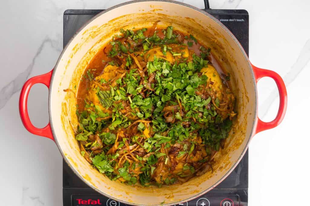cilantro and mint with fried onions topping cooked chicken biryani.