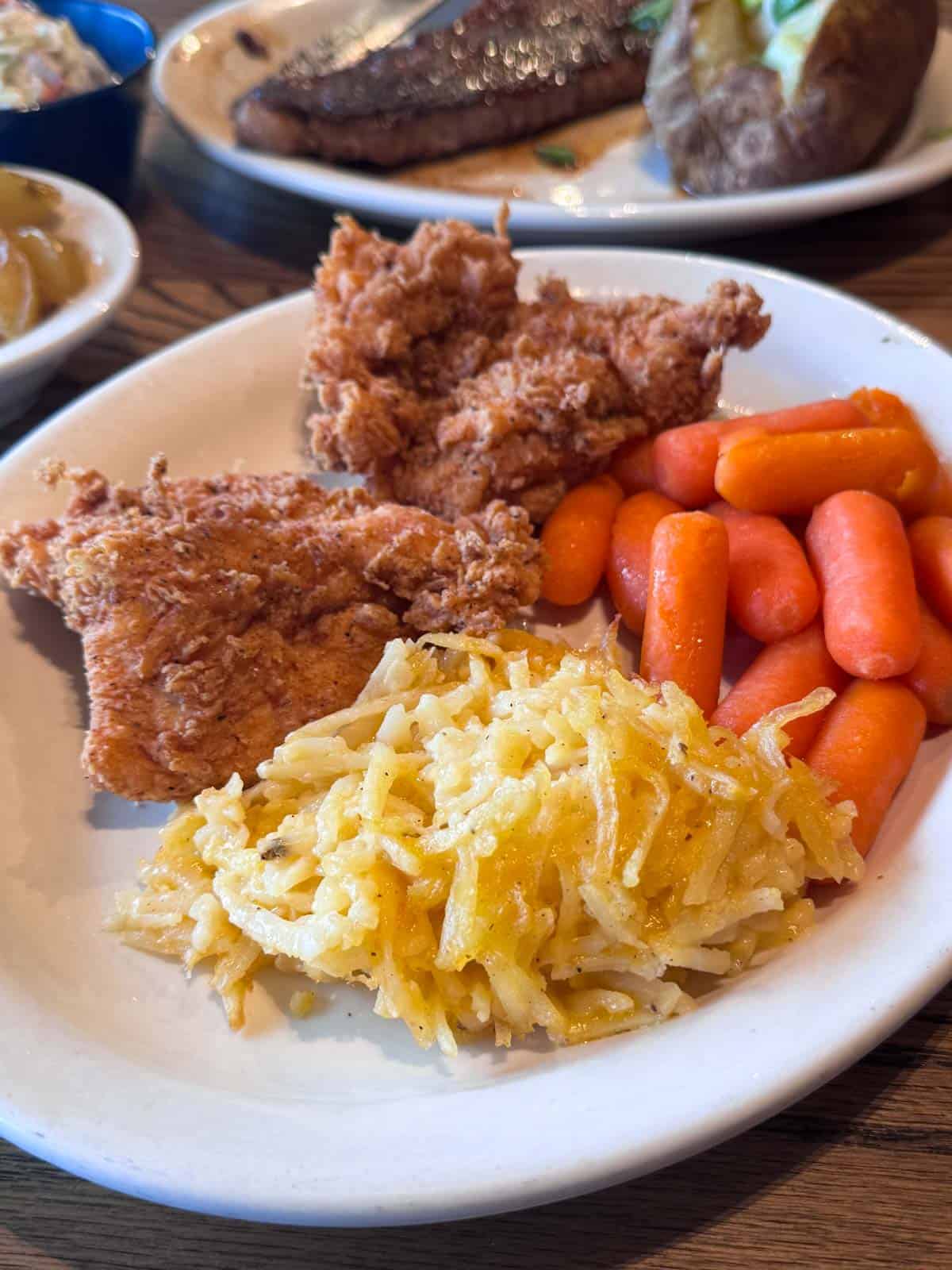 Cracker Barrel hashbrown casserole served as a side with fried chicken and carrots.