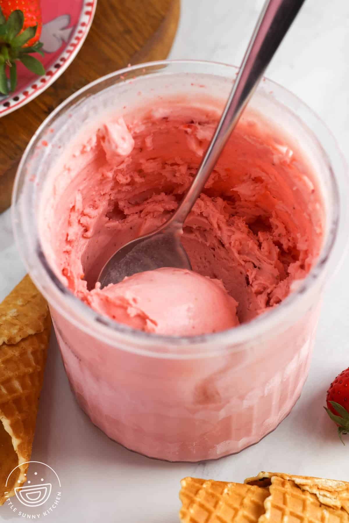 Spoon stirring creamy strawberry ice cream in a Ninja Creami pint