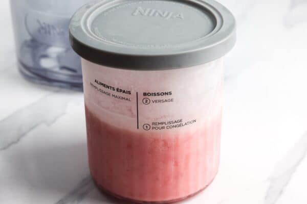 Ninja Creami pint filled with strawberry ice cream mixture and covered with a storage lid