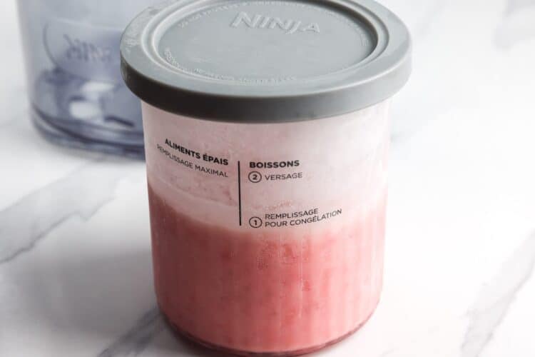Ninja Creami pint filled with strawberry ice cream mixture and covered with a storage lid
