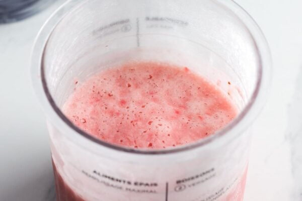Frozen strawberry ice cream base in a Ninja Creami pint