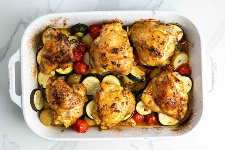 Roasted chicken thighs with potatoes, zucchini, and tomatoes after baking.