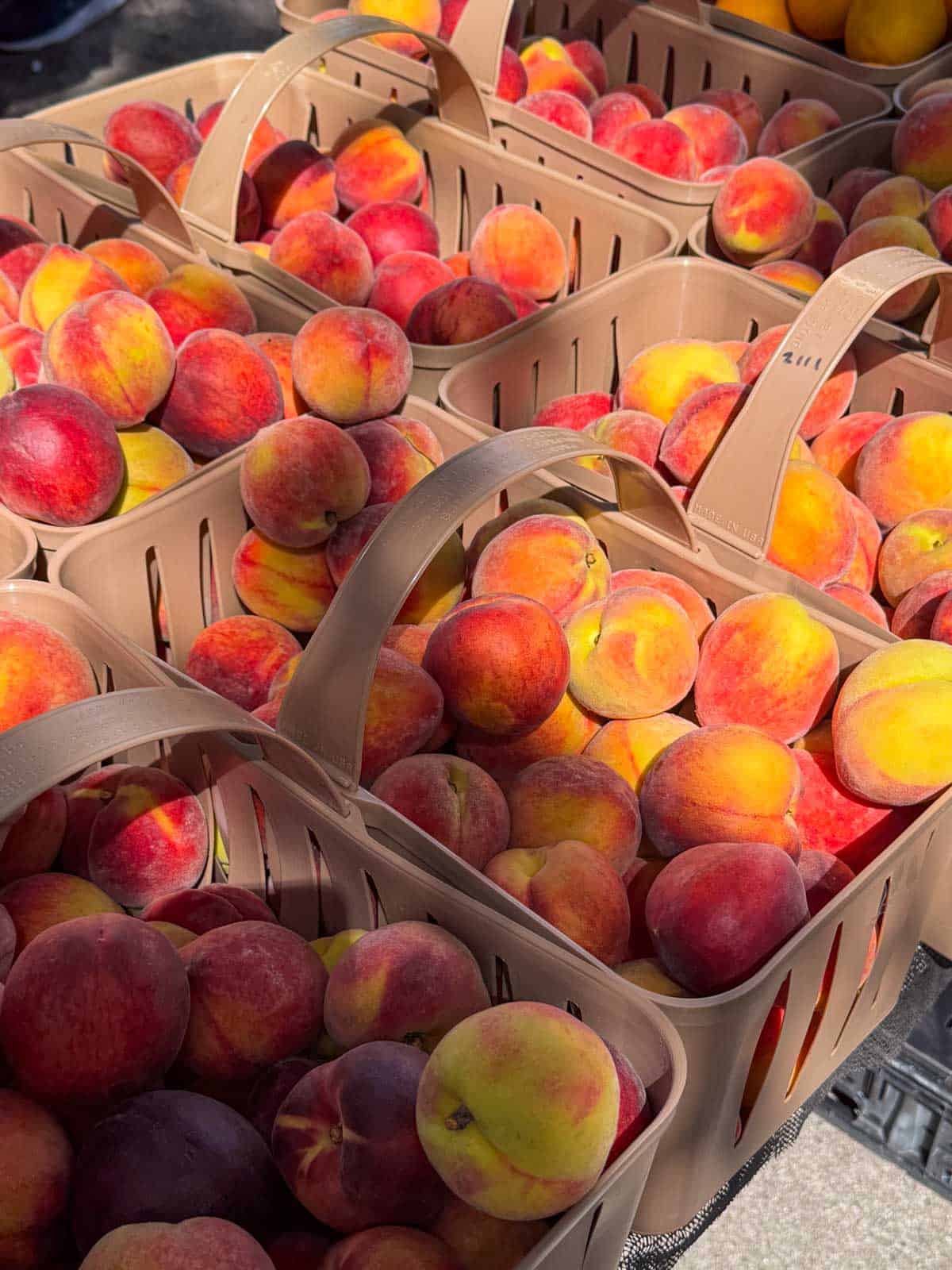 Baskets of ripe summer peaches at a farmers market