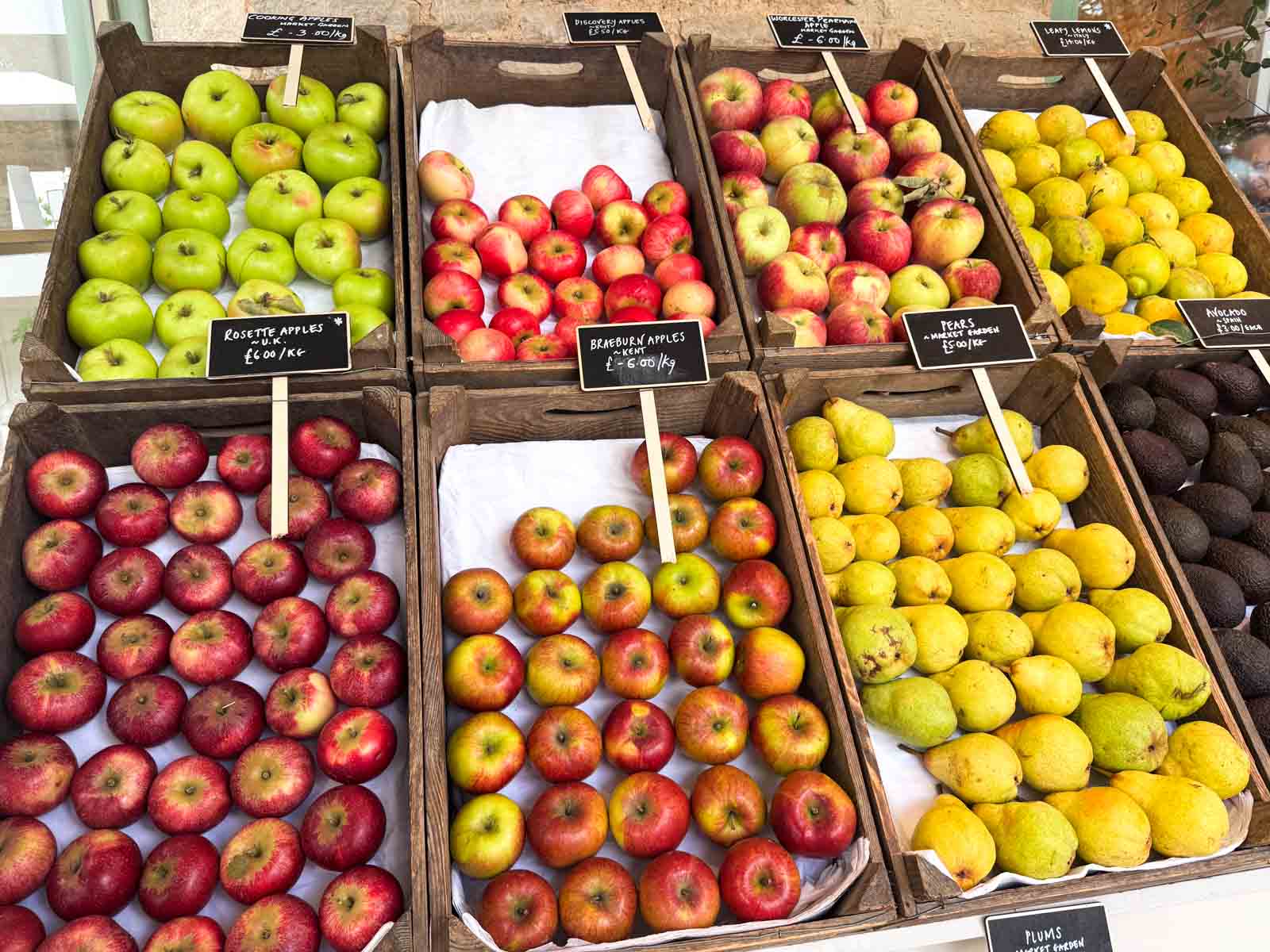 Display of seasonal apples and pears in wooden crates at a farmers market in early fall.