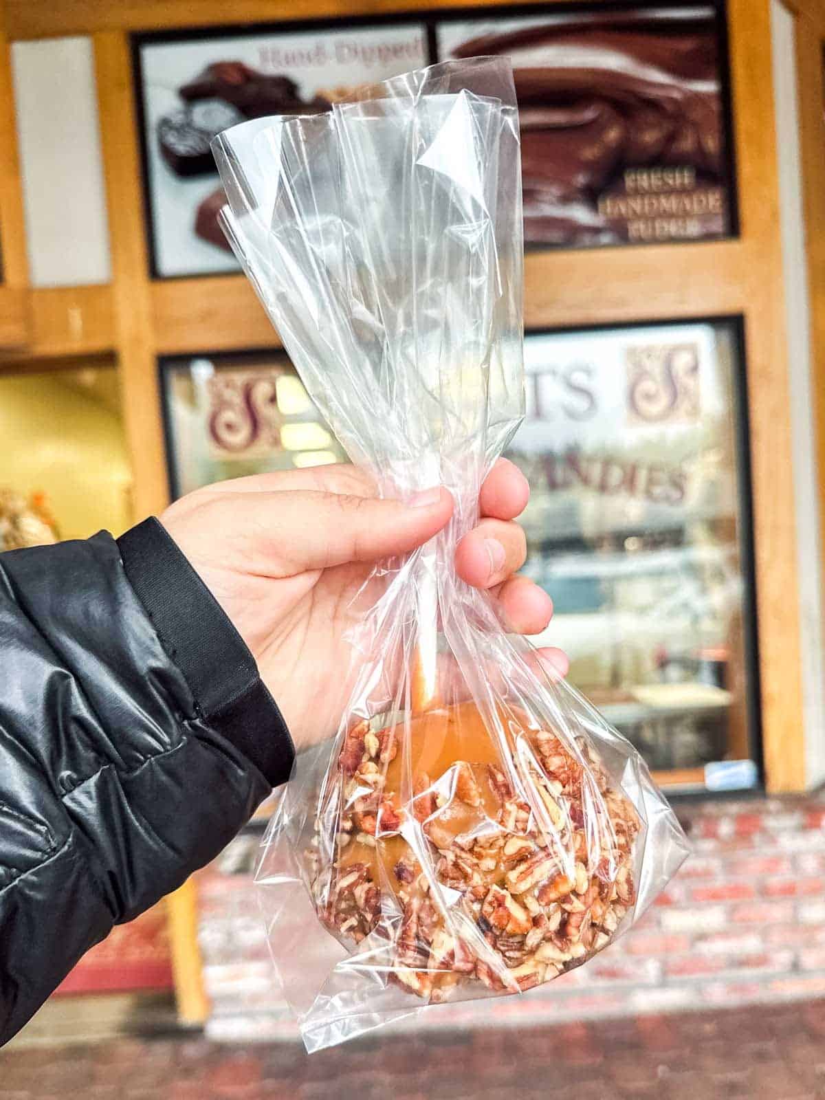 Caramel apple coated with chopped pecans at a fall market.