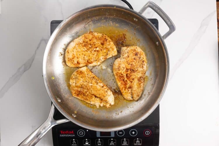chicken cutlets sauteed in a skillet.
