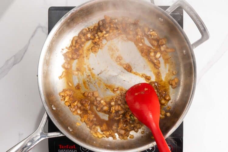 onion and garlic cooking in a pan with butter and chicken juices.