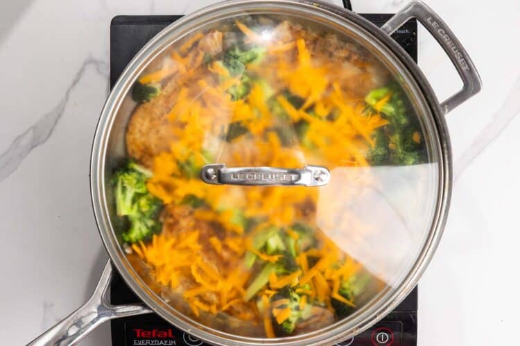 Cheese added to chicken and broccoli skillet. A lid is added so that the cheese will melt.