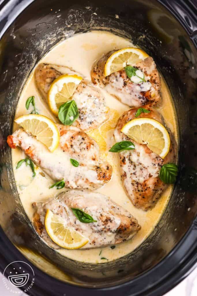slow cooker lemon chicken in a creamy sauce, garnished with fresh basil.