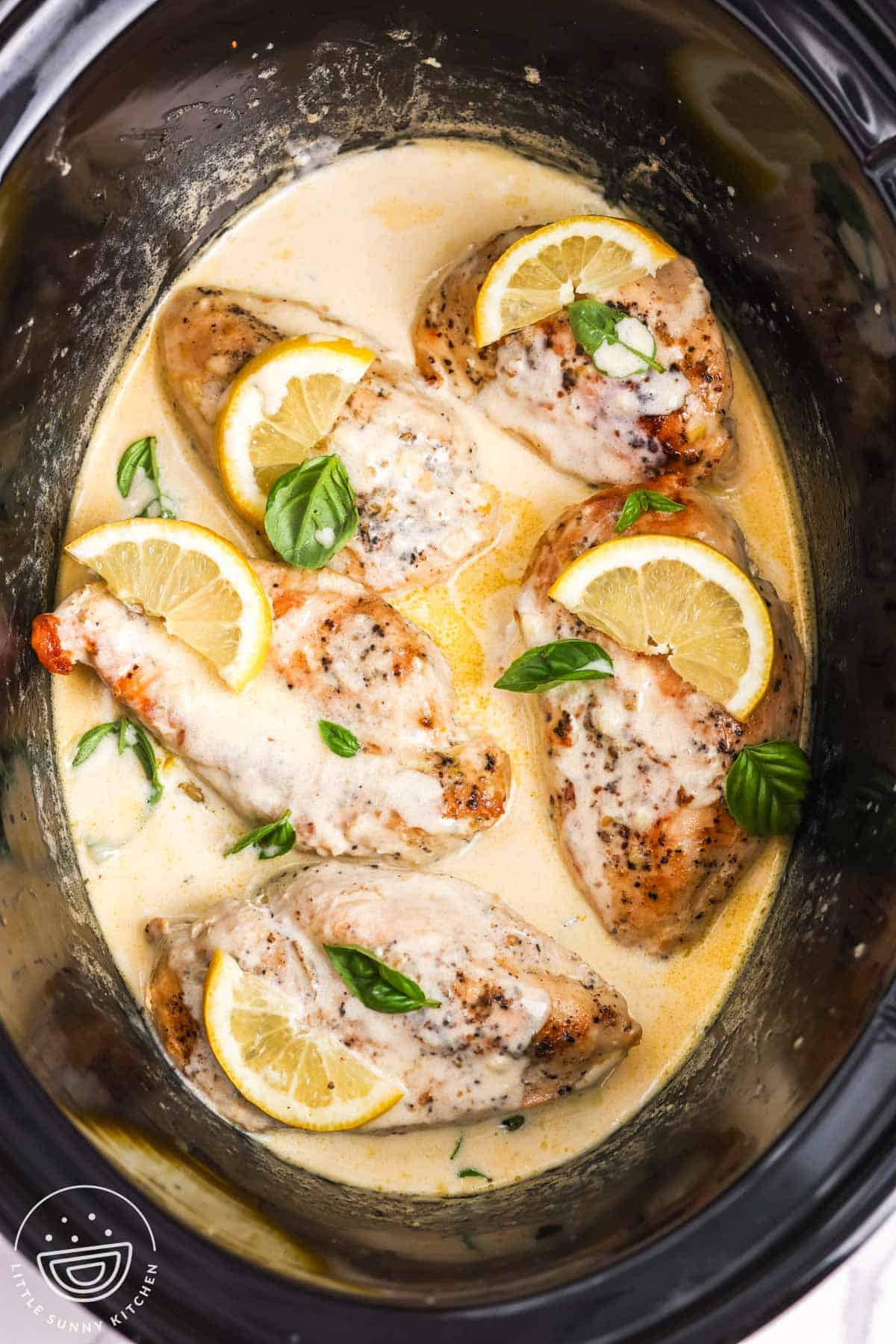 slow cooker lemon chicken in a creamy sauce, garnished with fresh basil.