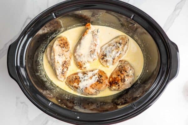 5 cooked chicken breasts in a crockpot with a creamy lemon sauce.