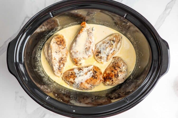 5 cooked chicken breasts in a crockpot with a creamy lemon sauce.