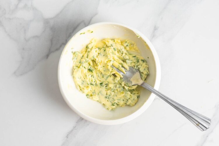 Garlic herb butter mixed in a small bowl for spreading over ciabatta bread.