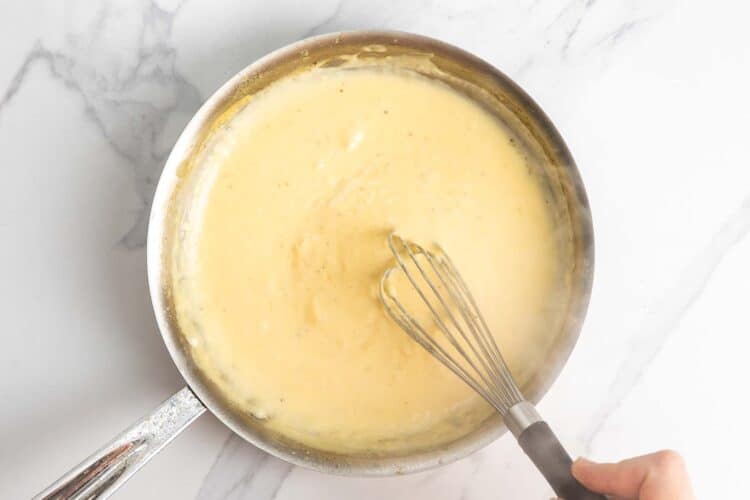Thick and creamy Alfredo sauce cooking in a skillet.