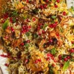 close up of A platter of chicken biryani over rice, garnished with pomegranate arils and crispy fried onions.