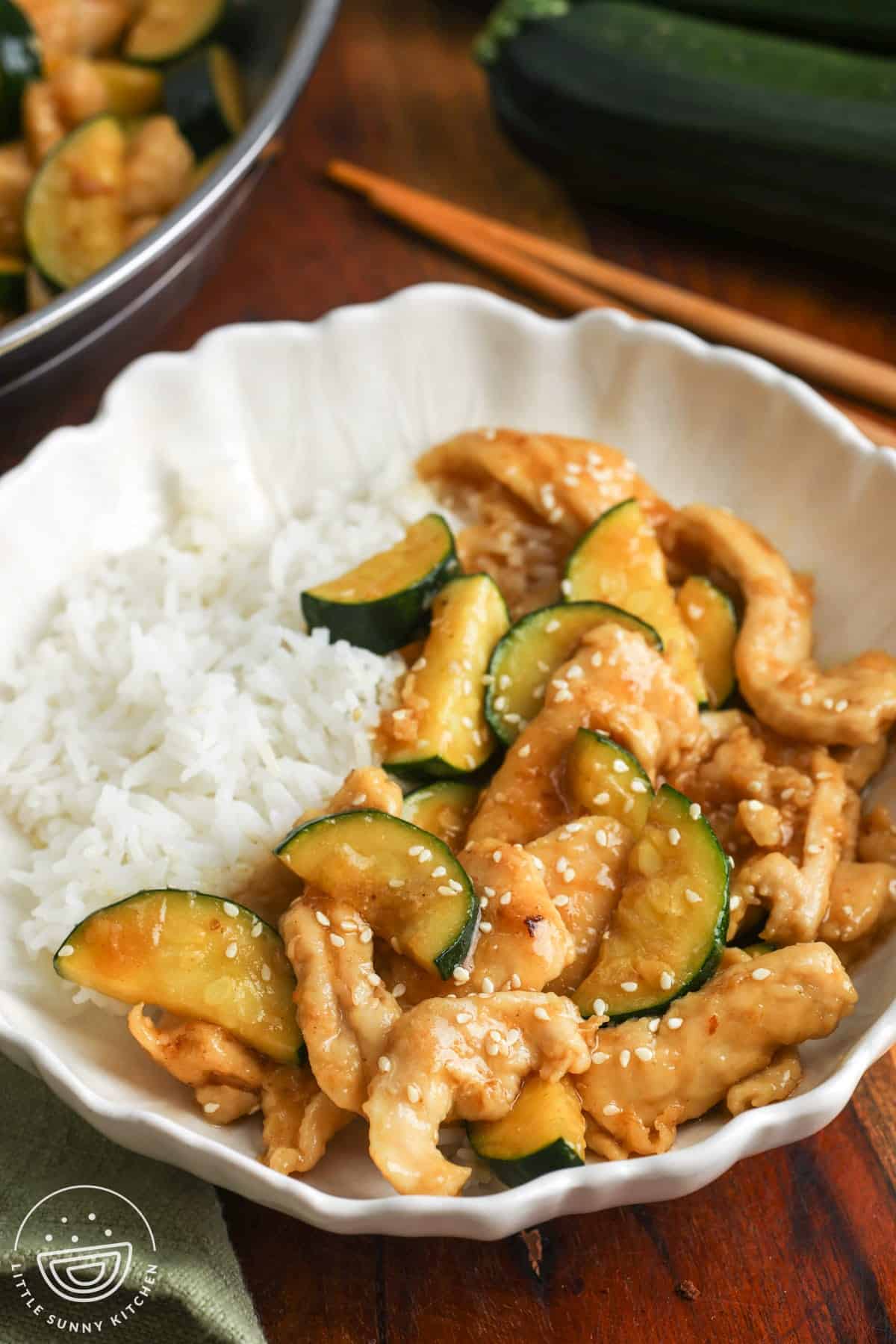 a ceramic bowl of chicken zucchini stir fry served over rice.