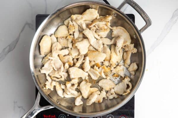 slices of chicken seared in a skillet.