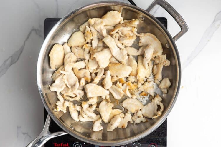 slices of chicken seared in a skillet.