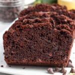 slices of double chocolate zucchini bread with chocolate chips on a white platter.