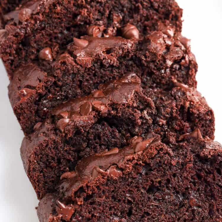 A loaf of chocolate zucchini bread with chocolate chips, sliced and viewed from overhead.