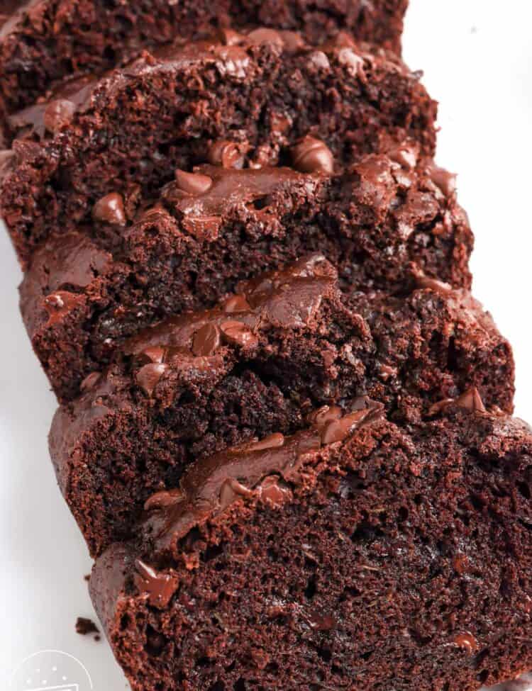A loaf of chocolate zucchini bread with chocolate chips, sliced and viewed from overhead.
