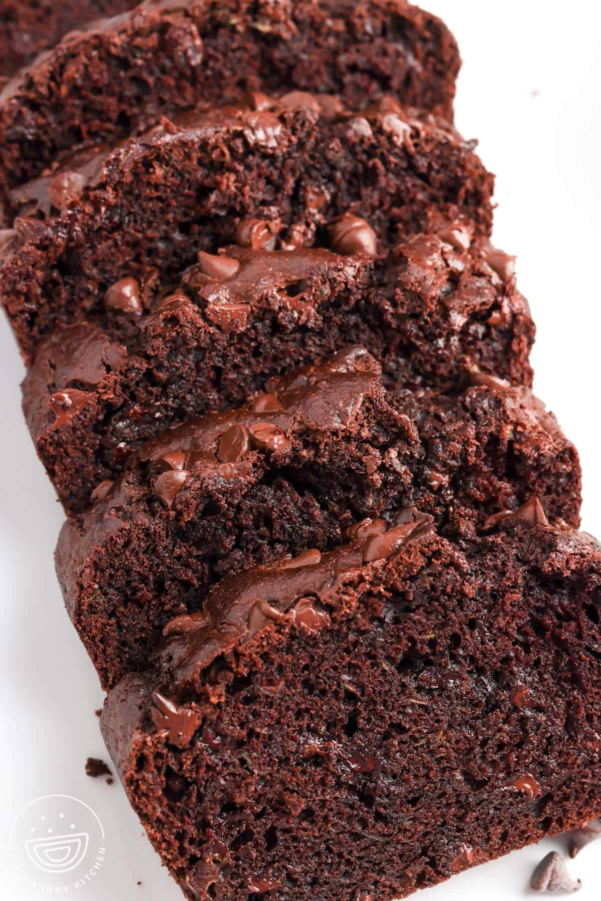 A loaf of chocolate zucchini bread with chocolate chips, sliced and viewed from overhead.