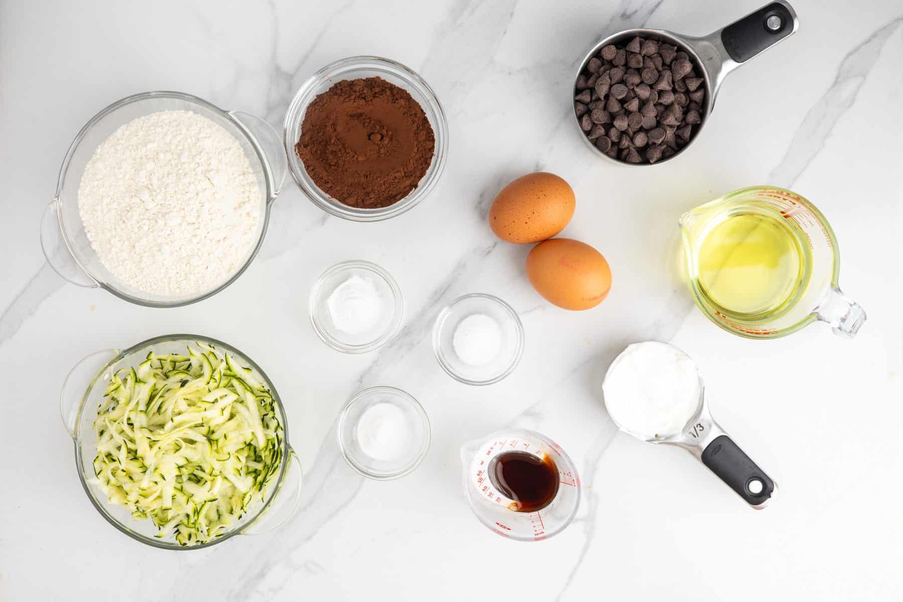 grated zucchini in a bowl along with other ingredients to make zucchini bread.