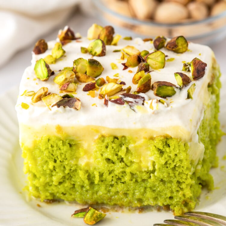 Close up of pistachio poke cake soaked with condensed milk and topped with pudding and whipped cream