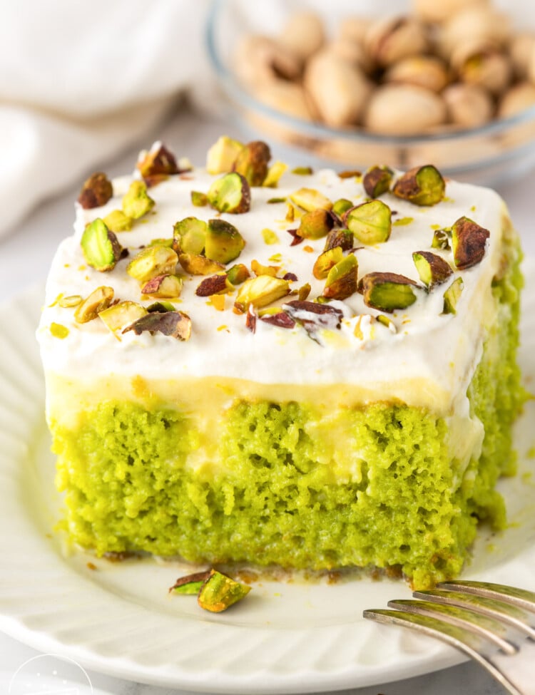 Close up of pistachio poke cake soaked with condensed milk and topped with pudding and whipped cream