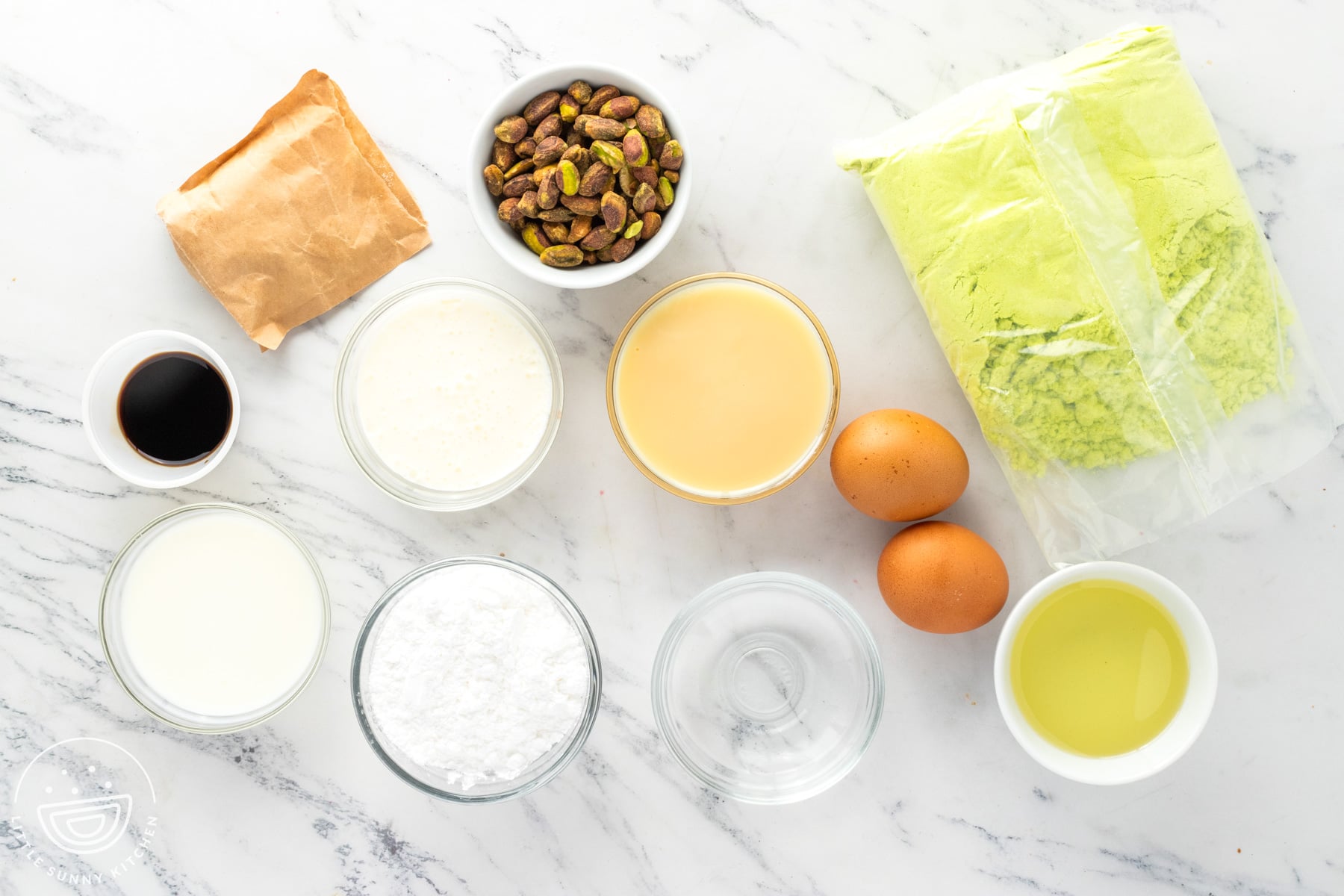 Ingredients for pistachio poke cake including cake mix, pudding, condensed milk, cream, and pistachios