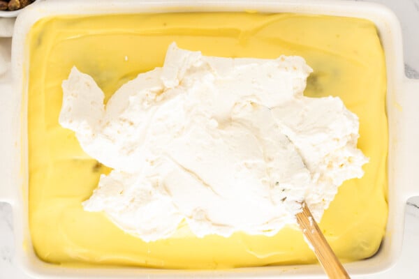 Spreading whipped cream over the chilled vanilla pudding layer