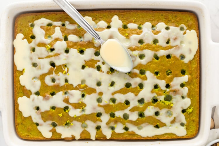Pouring sweetened condensed milk into holes in the pistachio cake