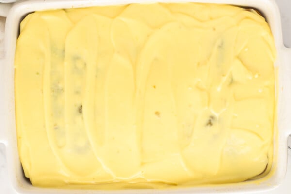 Smooth vanilla pudding layer covering the pistachio poke cake