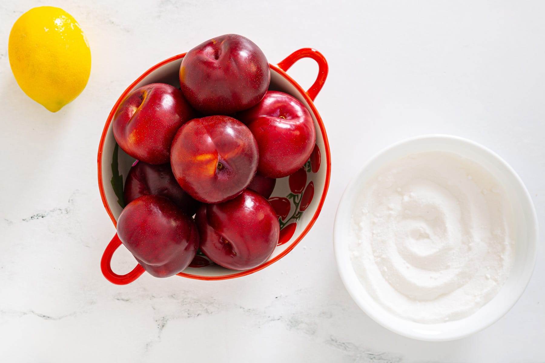 Fresh plums with sugar and lemon arranged for making plum jam.