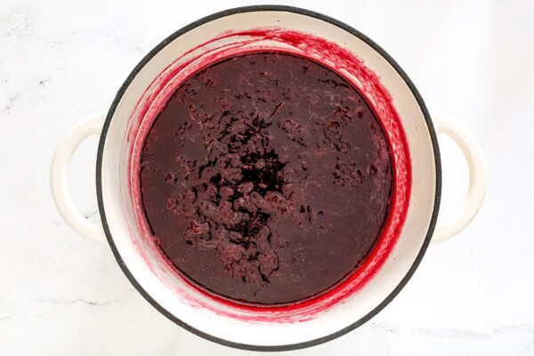 Thick cooked plum jam in a white heavy-bottomed pot
