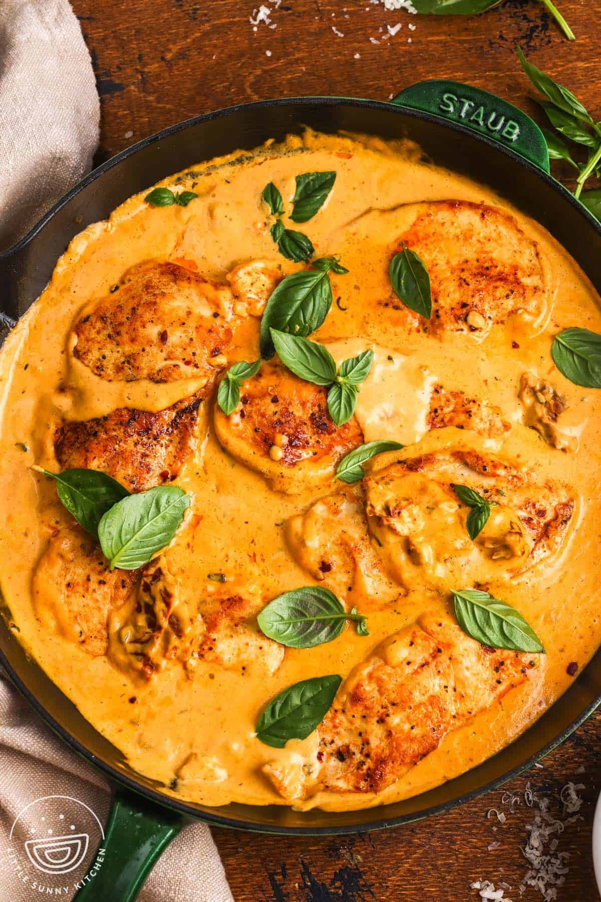 Overhead view of chicken cutlets simmered in creamy pumpkin Parmesan sauce and topped with fresh basil.