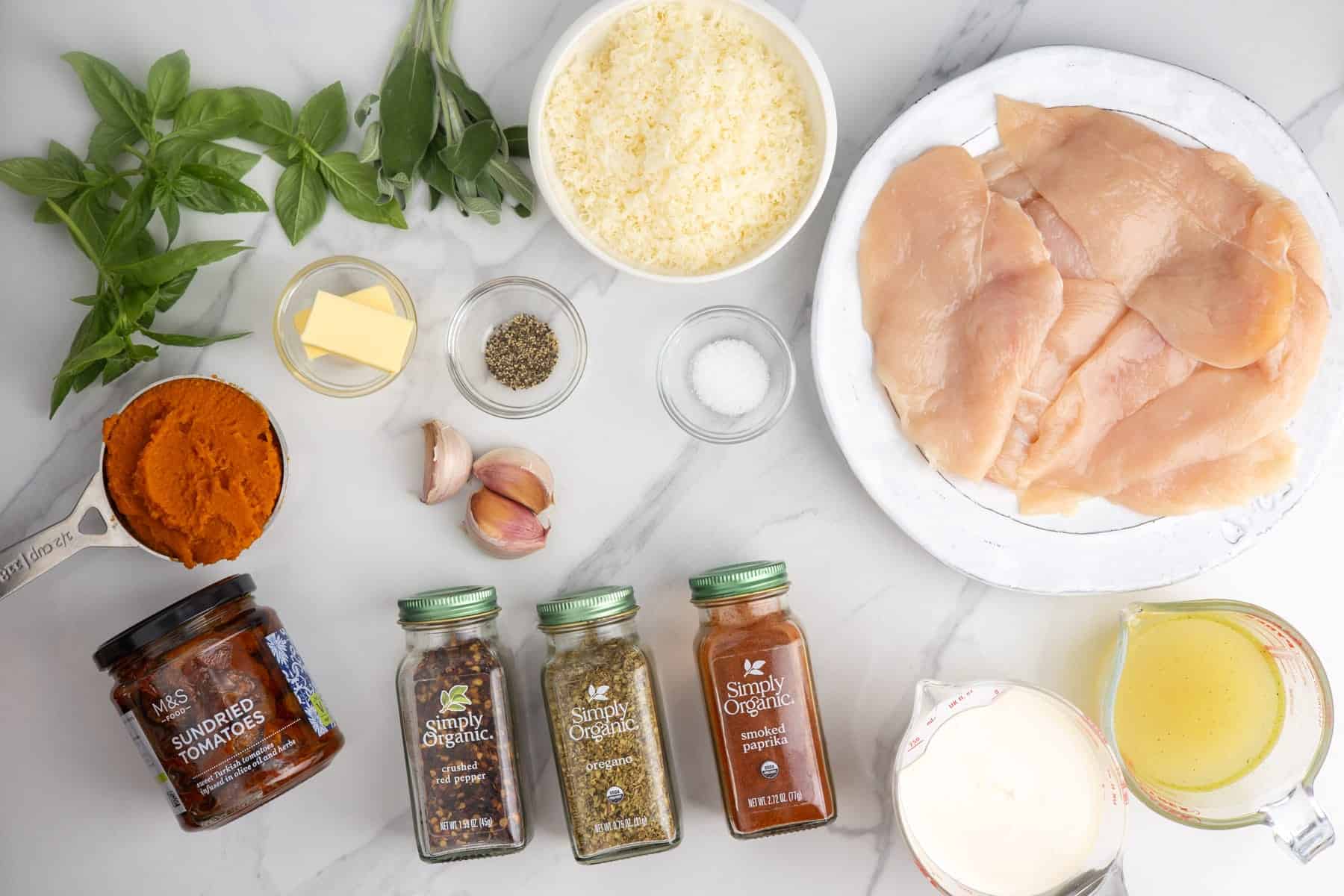 Ingredients for Pumpkin Marry Me Chicken, including chicken, pumpkin puree, sage, sun-dried tomatoes, cream, Parmesan, and seasonings.