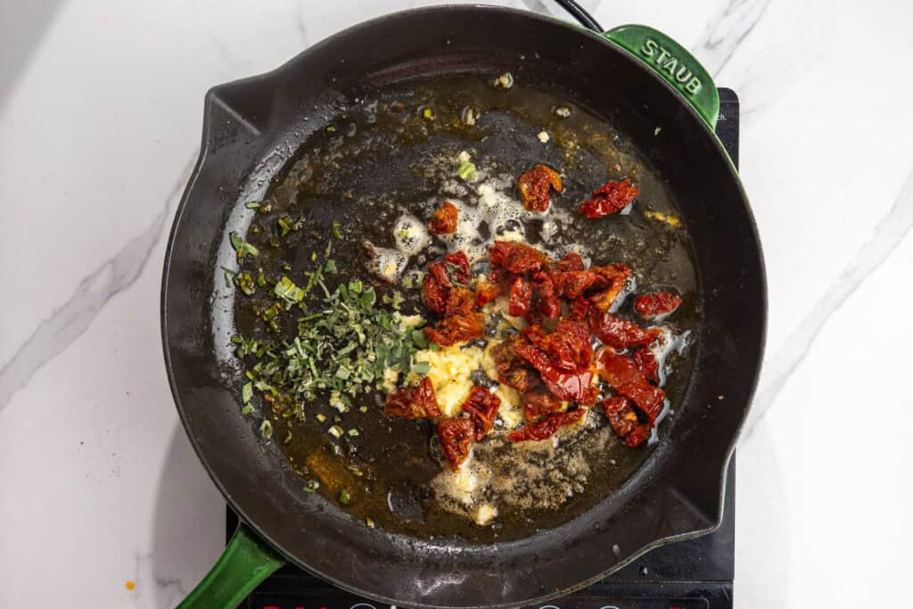 Garlic, chopped sage, and sun-dried tomatoes cooking in butter and tomato oil.