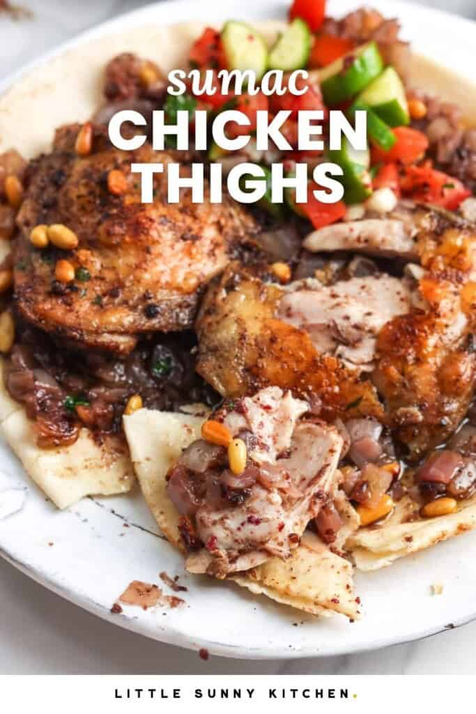 Sumac chicken thighs with onions, pine nuts, pita bread, and tomato cucumber salad.