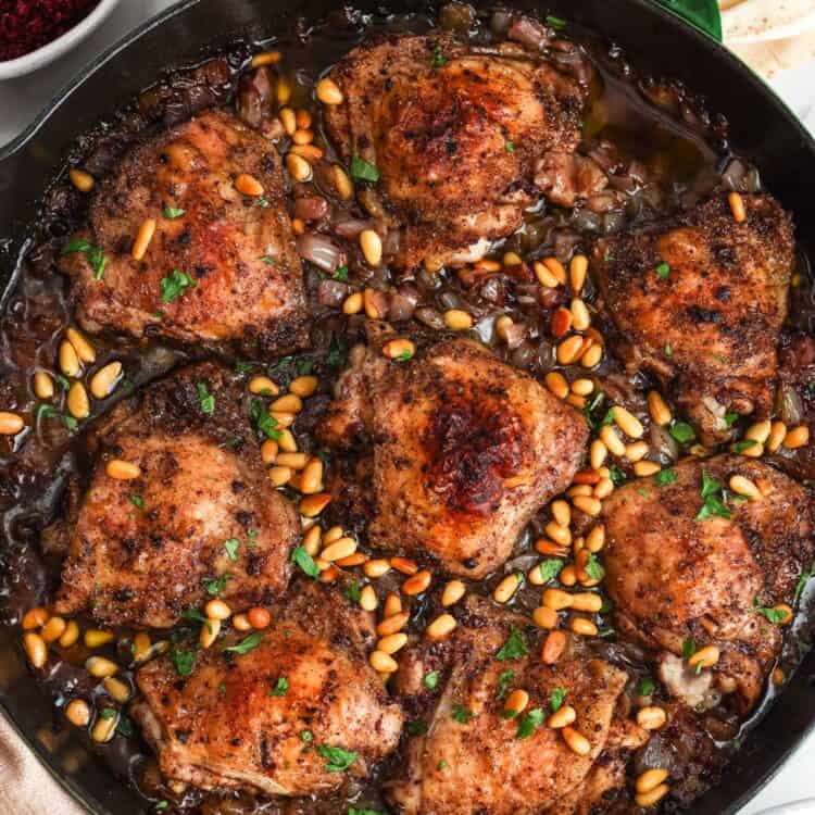Sumac chicken thighs baked with onions and topped with toasted pine nuts.