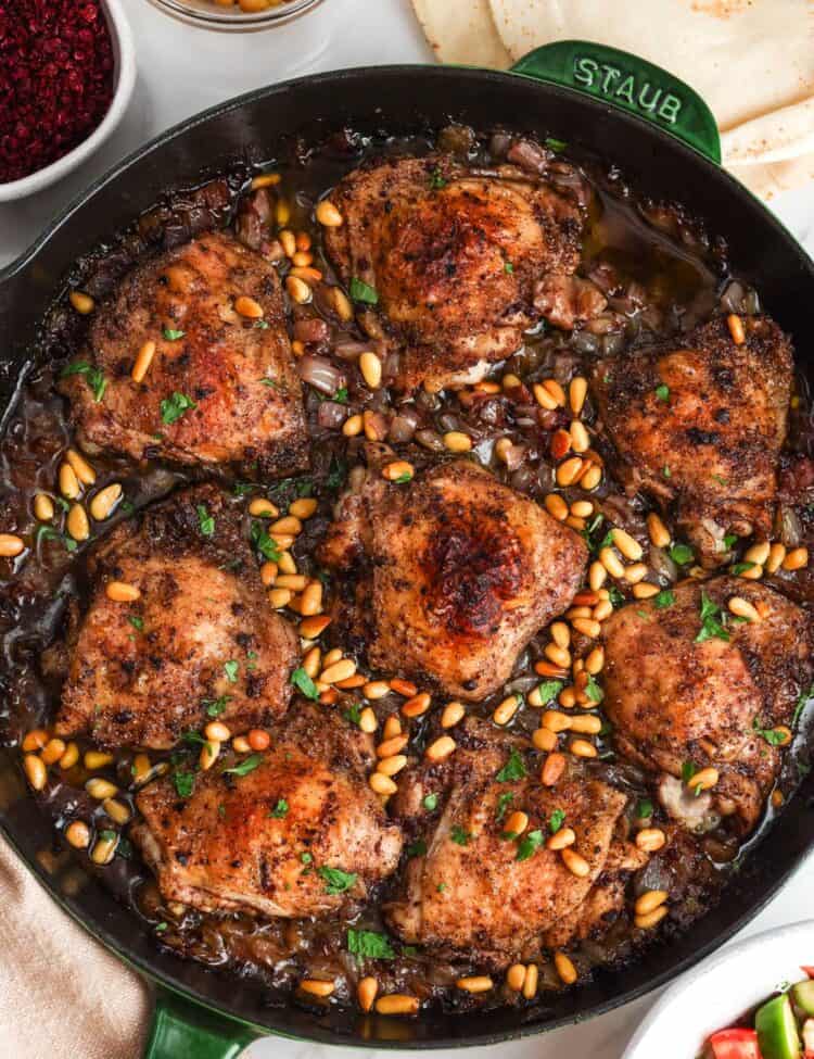 Sumac chicken thighs baked with onions and topped with toasted pine nuts.
