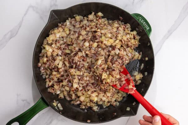 Softened onions mixed with sumac in a cast-iron skillet.