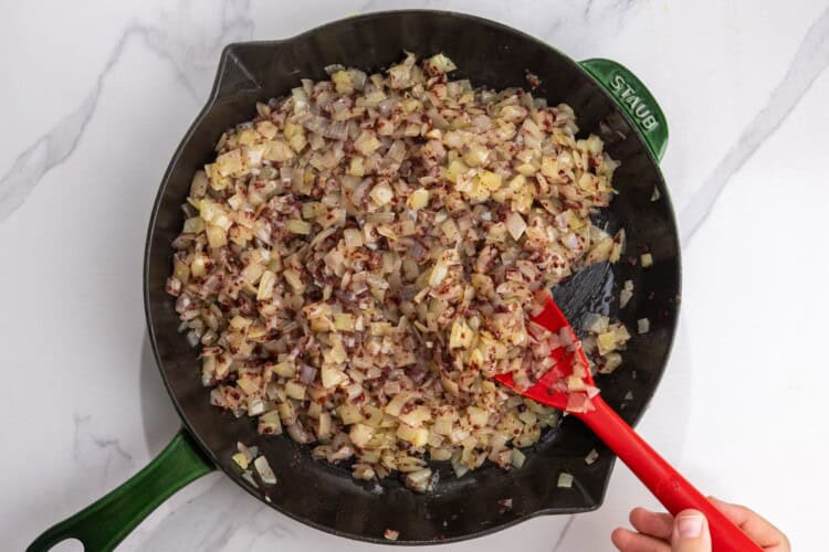 Softened onions mixed with sumac in a cast-iron skillet.