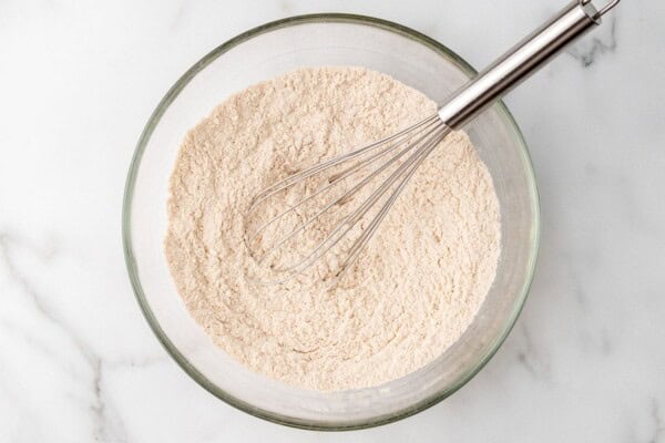 a bowl of flour mixed with cinnamon and leaveners with a whisk.